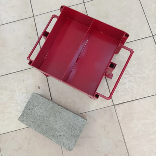 Hand-pressed steel maxi brick mould with two cavities beside a finished maxi brick